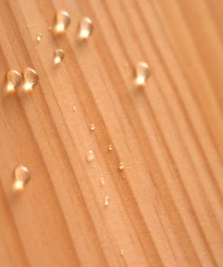 塗裝有撥水劑的木板以傾斜角度立起，數顆水珠從上而下沿木板滑落無滲入情形