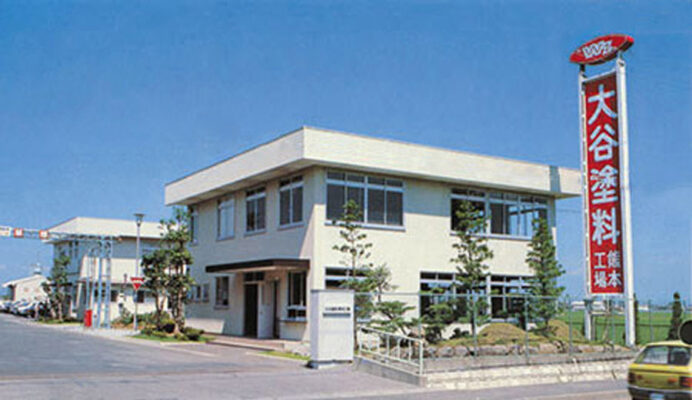 大谷塗料熊本工廠，白色的兩層樓工廠與紅色直立招牌